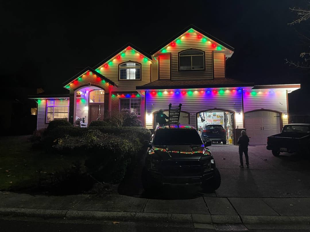 Holiday exterior lighting installation on residential home at night